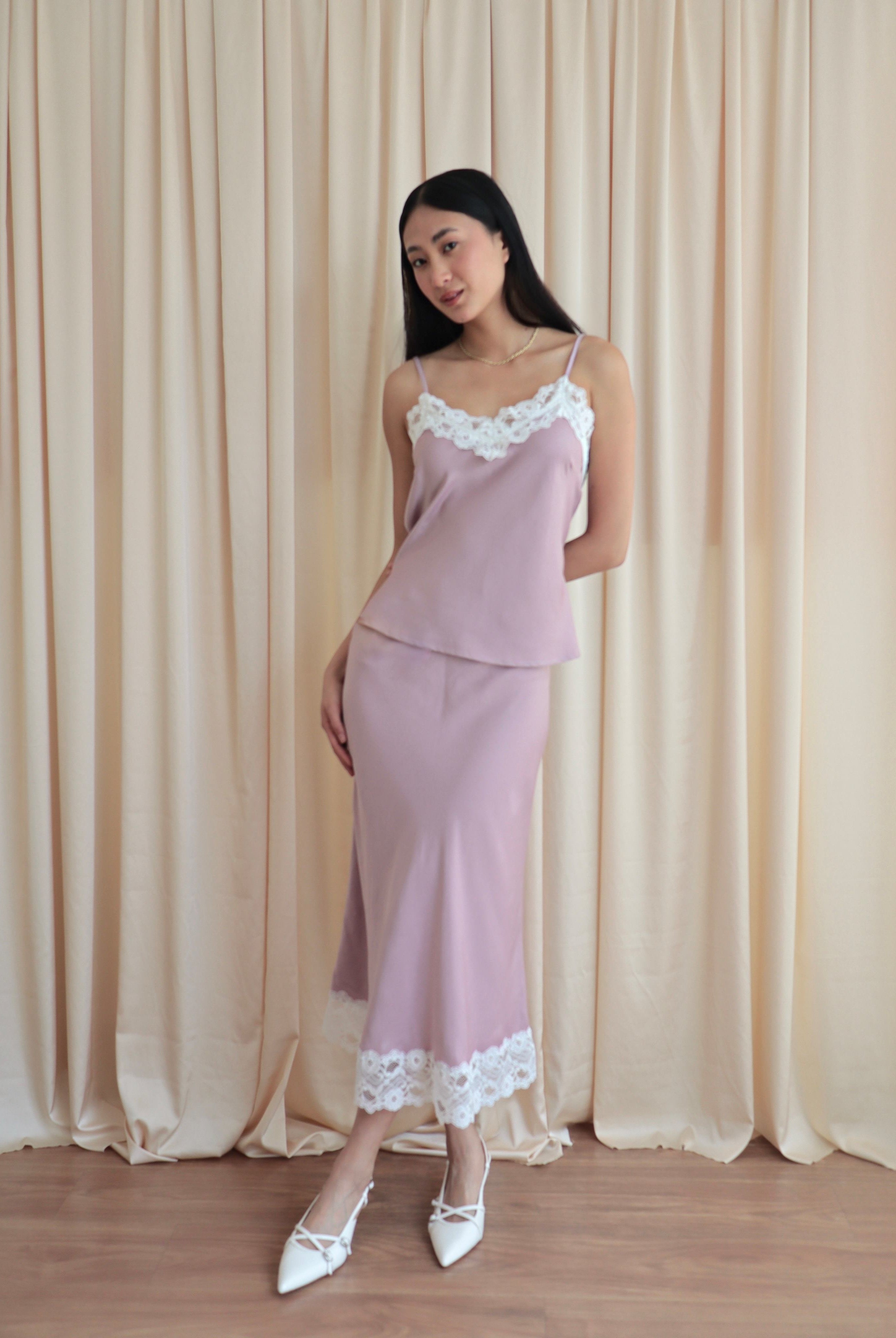 Mujer usando conjunto de top y falda midi lencero rosa romántico en fondo amarillo