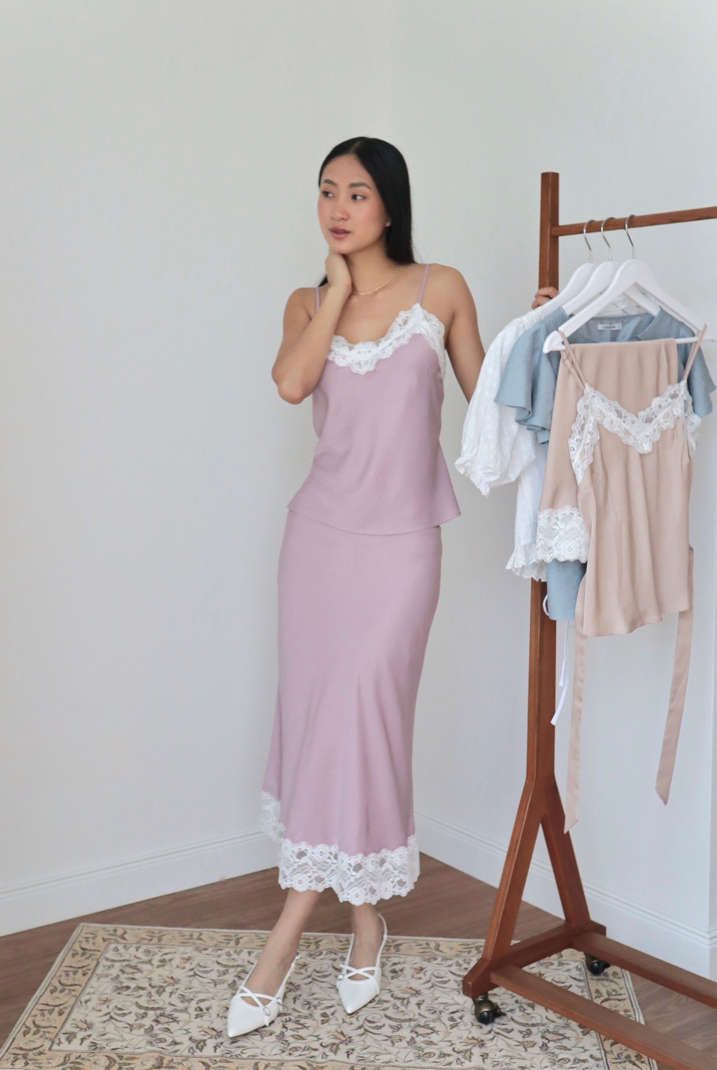 Mujer usando conjunto de top y falda midi lencero rosa romántico con fondo blanco