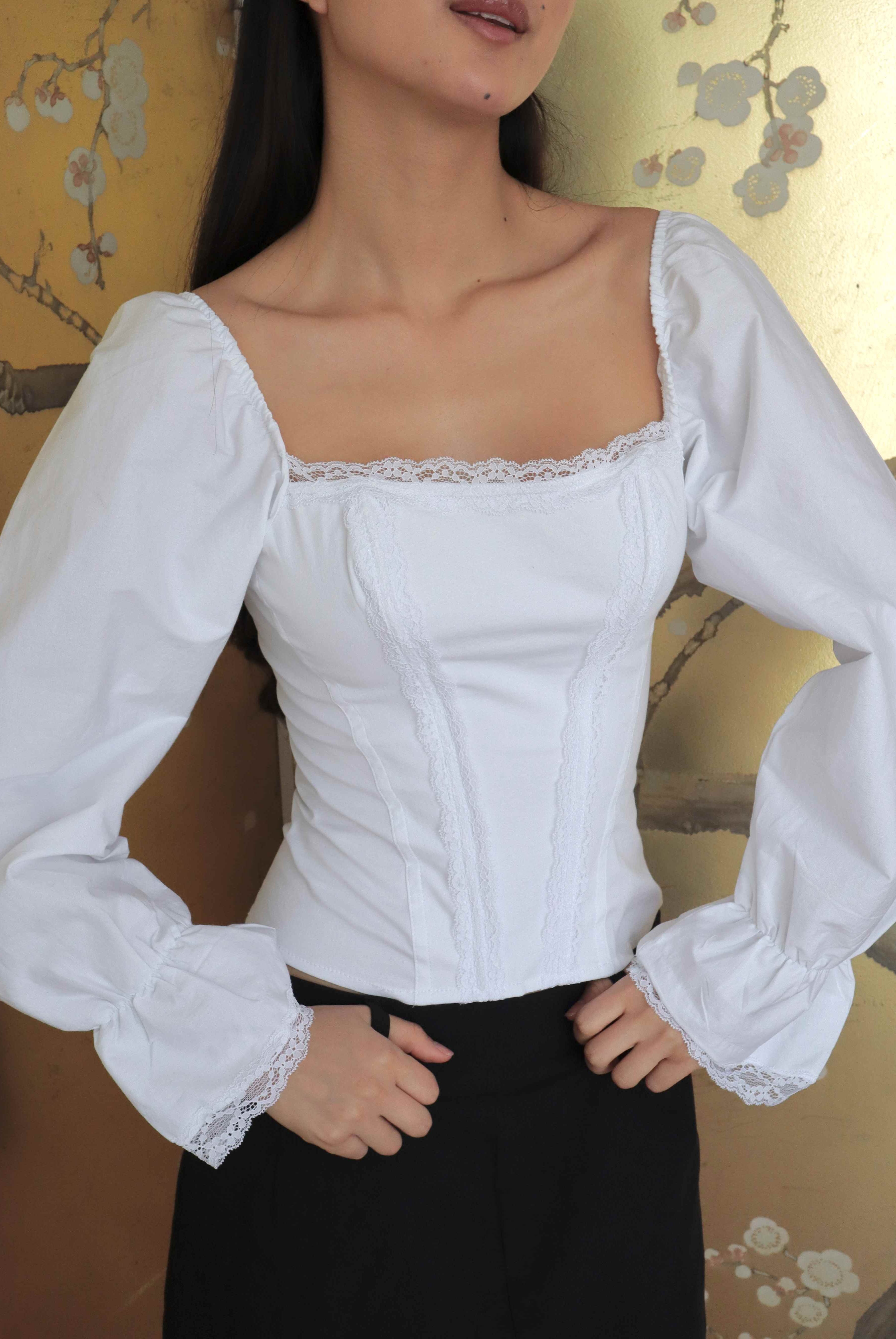 Mujer usando corset de algodón, mangas largas y blondas. Posando en fondo floral.