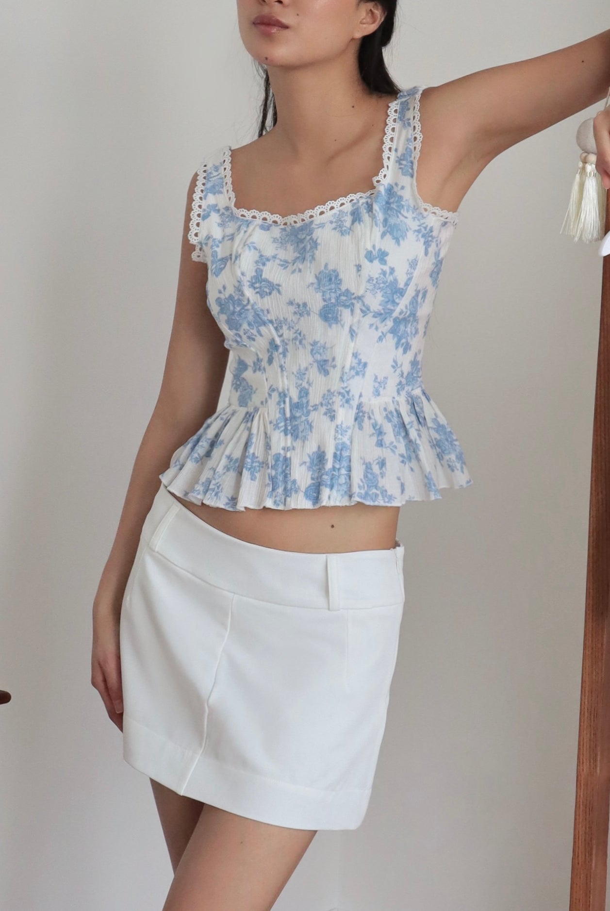 Mujer con corset romántico ceñido al cuerpo estampado flores celestes y falda blanca. Posando en fondo blanco.