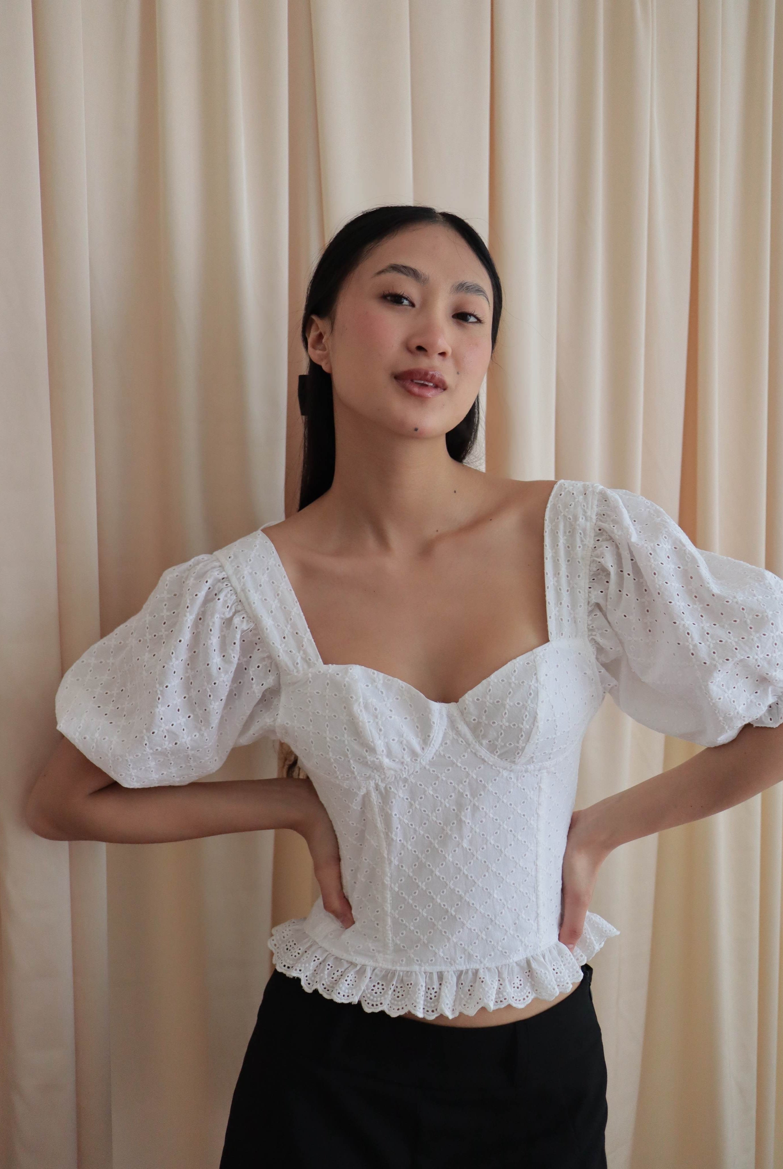 Mujer con corset broderie con escote corazón, mangas abullonadas y blonda. Posando en fondo amarillo pastel