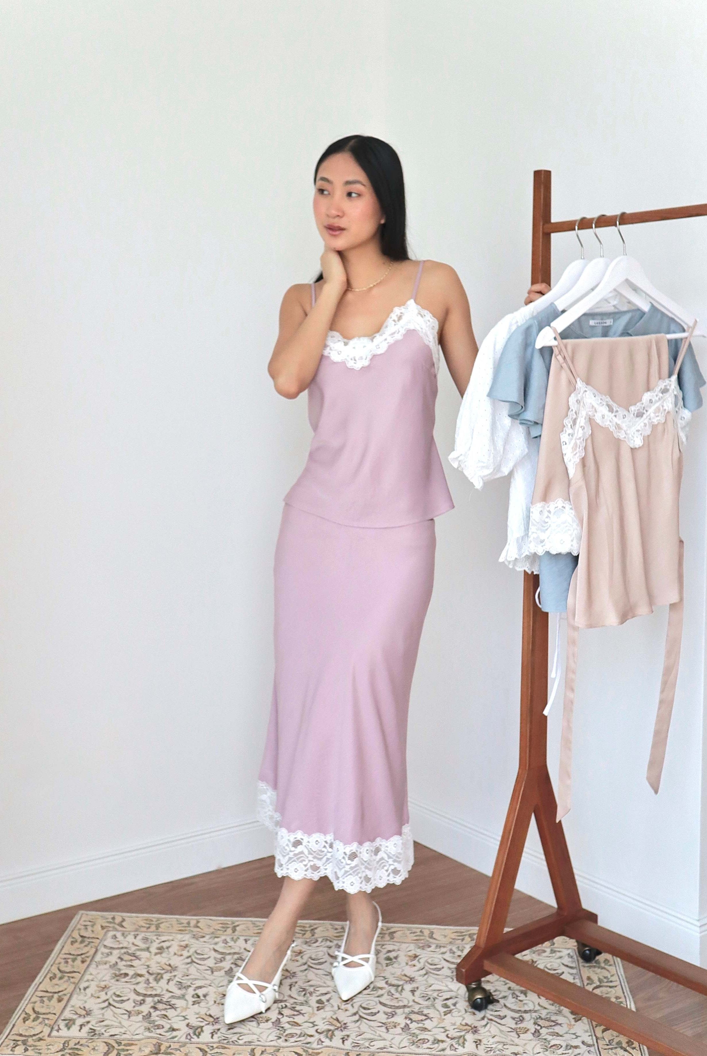 Mujer usando conjunto de top y falda midi lencero rosa romántico en fondo amarillo