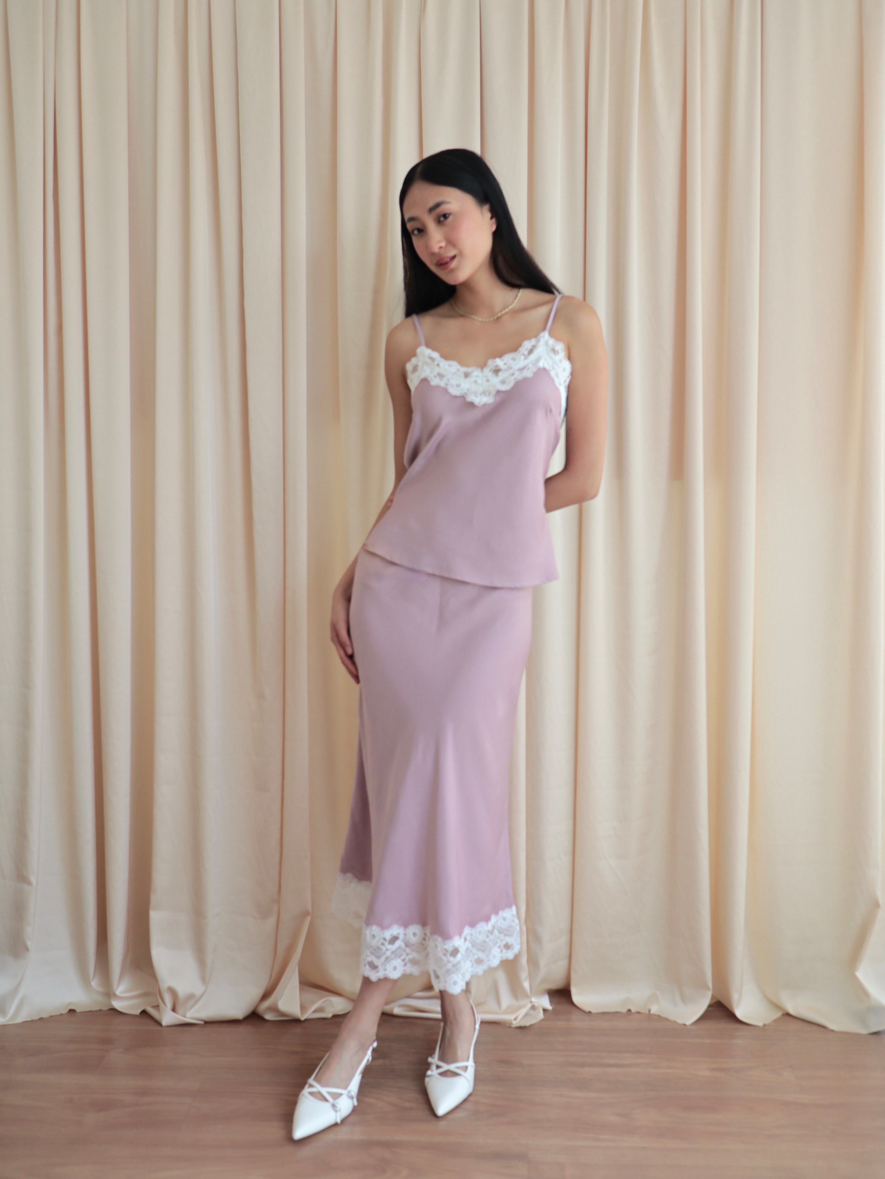 Mujer usando conjunto de top y falda midi lencero rosa romántico en fondo amarillo