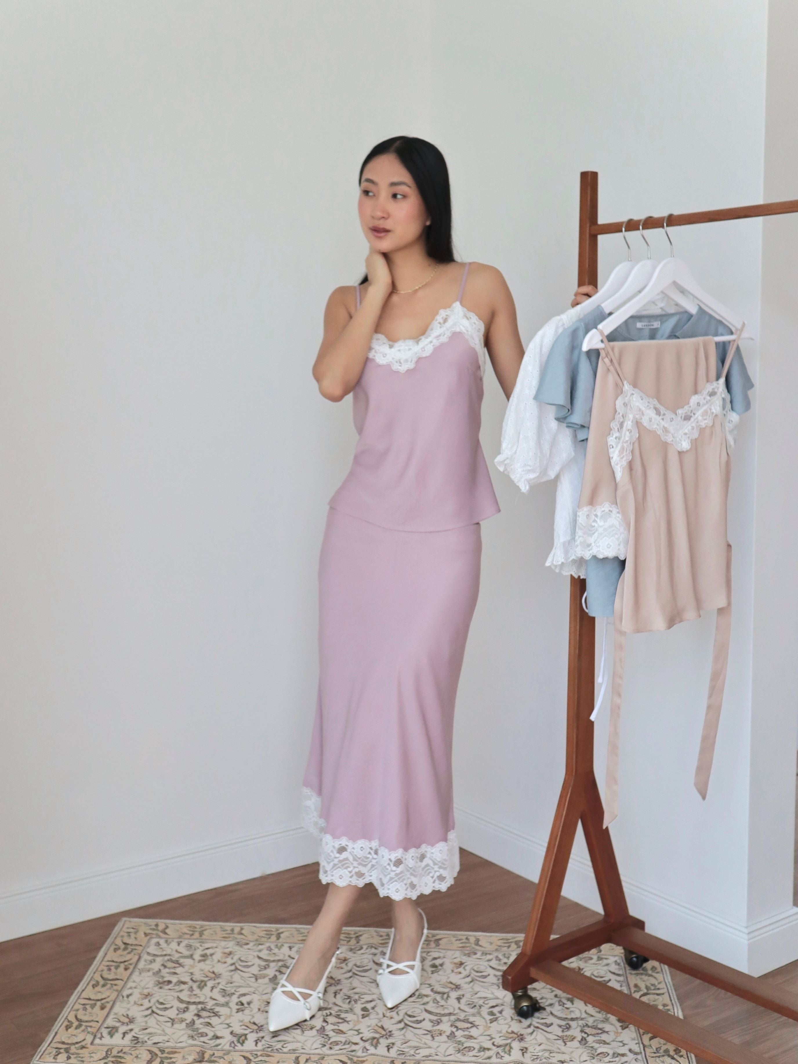 Mujer usando conjunto de top y falda midi lencero rosa romántico con fondo blanco