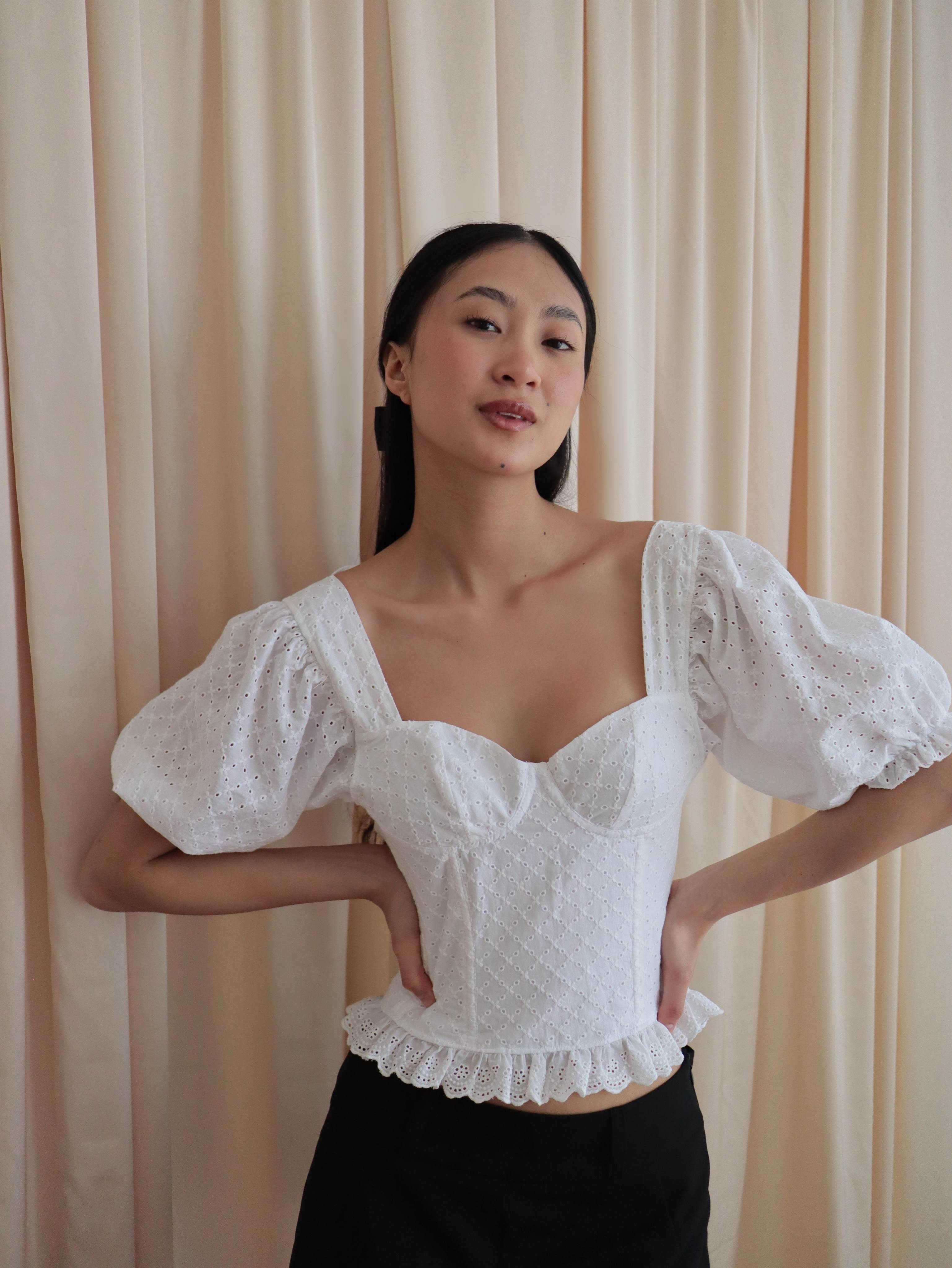 Mujer con corset broderie con escote corazón, mangas abullonadas y blonda. Posando en fondo amarillo pastel