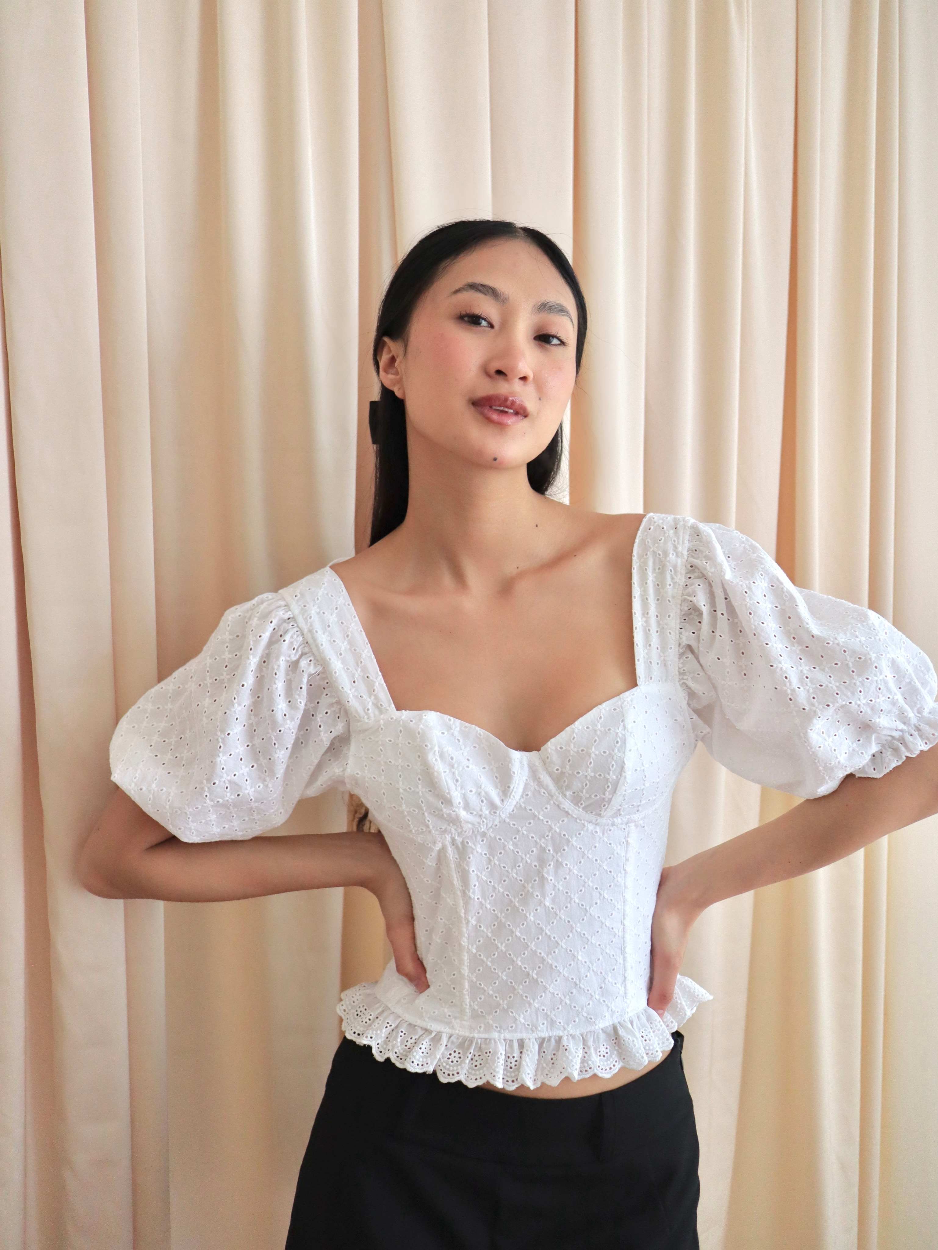 Mujer con corset broderie con escote corazón, mangas abullonadas y blonda. Posando en fondo amarillo pastel