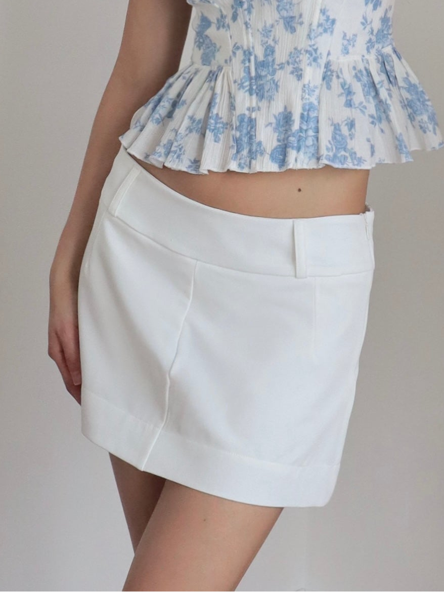 Mujer usando falda short blanca debajo de la cintura en fondo blanco